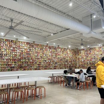 The Ramyun Library - a man in a yellow jacket standing in front of a wall of books - Ramen Near Me - Carrollton, Texas The Ramyun Library - a man in a yellow jacket standing in front of a wall of books - Ramen Near Me - Carrollton, Texas