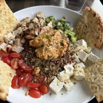 Modern Plate - grain bowl - A grain bowl containing cherry tomatoes, chopped cucumbers, feta cheese cubes, grilled chicken pieces, and pita bread slices, served on a white plate. - Cocktail Bars Near Me - Elmhurst, Illinois