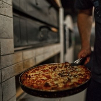 Bow Tie Pizza - a man pulling a pizza out of the oven - Pizza Near Me - Calgary, Alberta Bow Tie Pizza - a man pulling a pizza out of the oven - Pizza Near Me - Calgary, Alberta