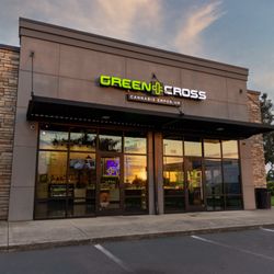 Green Cross Cannabis Emporium - Green Cross storefront at dusk with illuminated sign.