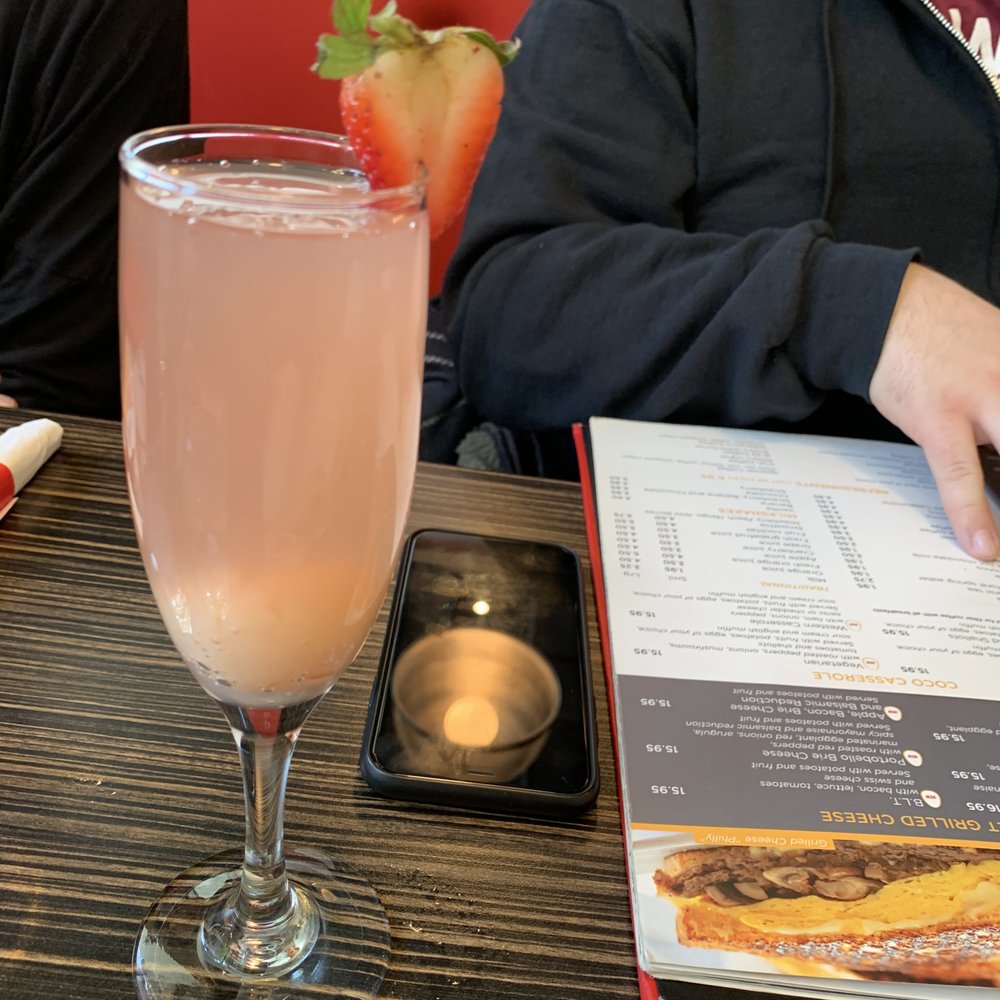Allô! Mon Coco - a person sitting at a table with a drink and a menu - Breakfast & Brunch Near Me - Montreal, Quebec