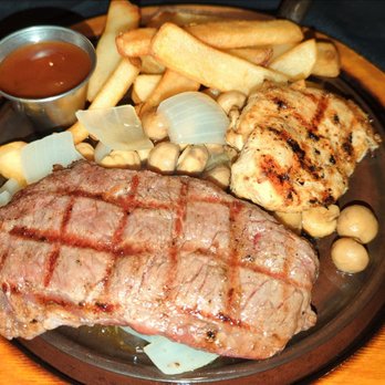 The Ribeye - 10 oz ribeye and 4 oz chicken.  Onions and mushrooms on a sizzling skillet - Steakhouses Near Me - Champaign, Illinois