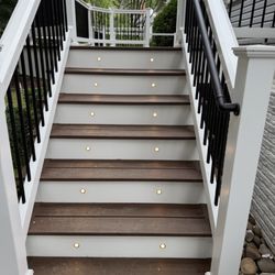 MH Remodeling - Custom deck renovation with new decking, white railing, black balusters & stair lighting. Built by Manassas Home Remodeling LLC.