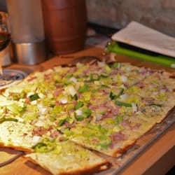 Flambee - Flambée: gut belegte, vorgeschnittene Flammkuchen auf dem Holzbrett.