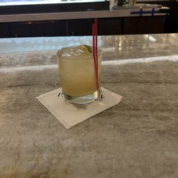 a glass of cocktail with a straw and a lime garnish