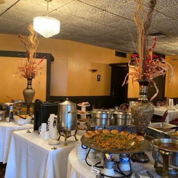 Maharaja - Buffet table at Maharaja Indian restaurant features decorative vases, chafing dishes, and a variety of food items in a dining area. - Indian Near Me - Milwaukee, Wisconsin
