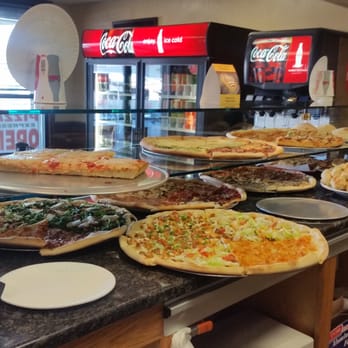 Pizza Express - a woman standing in front of a counter full of pizzas - Pizza Near Me - Florida, New York Pizza Express - a woman standing in front of a counter full of pizzas - Pizza Near Me - Florida, New York