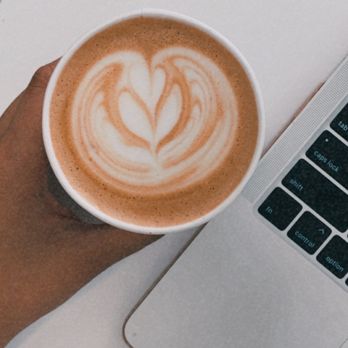 Sovereign Coffee - a person holding a cup of coffee in front of a laptop - Coffee & Tea Near Me - Brownsville, Texas Sovereign Coffee - a person holding a cup of coffee in front of a laptop - Coffee & Tea Near Me - Brownsville, Texas