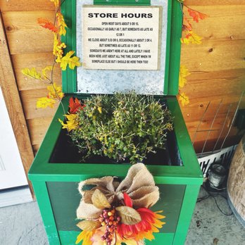 Adventure Distilling - a green planter with a sign that says store hours - Distilleries Near Me - Cosby, Tennessee