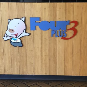 Four Plus 3 Korean BBQ - A sign for Four Plus 3 Korean BBQ features a cartoon pig mascot and colorful text on a wooden wall. - Korean Near Me - Eugene, Oregon