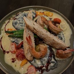 Squid ink ravioli with shrimp and chipotle cream cheese in a white suace and veggies with sourdough bread