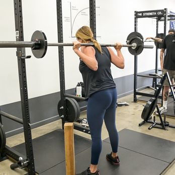 The Strength Co. - Costa Mesa - Starting Strength Coach Jeff Hairston teaches a lifter knee position in the squat during an intro to barbells - Trainers Near Me - Costa Mesa, California The Strength Co. - Costa Mesa - Starting Strength Coach Jeff Hairston teaches a lifter knee position in the squat during an intro to barbells - Trainers Near Me - Costa Mesa, California