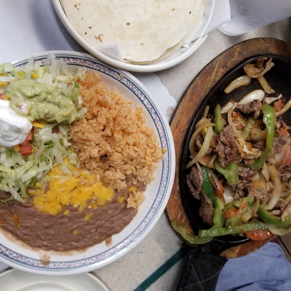 Mama Chus - Beef fajitas. Steaming beef on a hot cooking skillet, sides on another plate, and another plate for tortillas. You make your own tacos. - Mexican Near Me - Orem, Utah Mama Chus - Beef fajitas. Steaming beef on a hot cooking skillet, sides on another plate, and another plate for tortillas. You make your own tacos. - Mexican Near Me - Orem, Utah