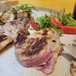 Undercooked pork steak with vegetables.