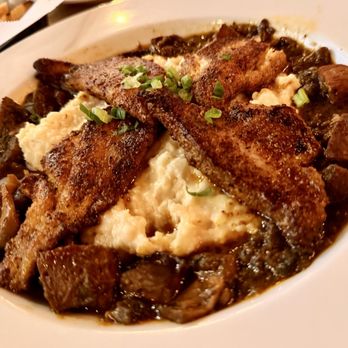 Lola's A Louisiana Kitchen - Catfish and Grits Seasoned pan-bronzed Mississippi catfish served over Gouda grits with Andouille pork sausage and mushroom ragout. - Cajun/Creole Near Me - Las Vegas, Nevada Lola's A Louisiana Kitchen - Catfish and Grits Seasoned pan-bronzed Mississippi catfish served over Gouda grits with Andouille pork sausage and mushroom ragout. - Cajun/Creole Near Me - Las Vegas, Nevada