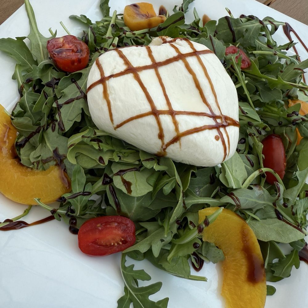 Peach and Burrata salad - 4 very thin peach slices and 2 grape tomatoes cut in half Peach and Burrata salad - 4 very thin peach slices and 2 grape tomatoes cut in half