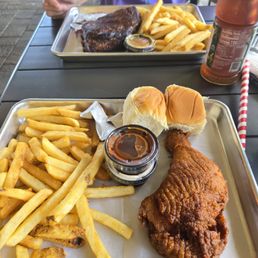 Foreground: 1/4 fried chicken, fries and rolls. Background ribs.