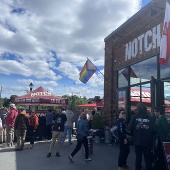 Notch Brewing - Crowd of people outside Notch Brewing in Salem, MA, with a tent, flags, and a brick building, under a partly cloudy sky. - Breweries Near Me - Salem, Massachusetts
