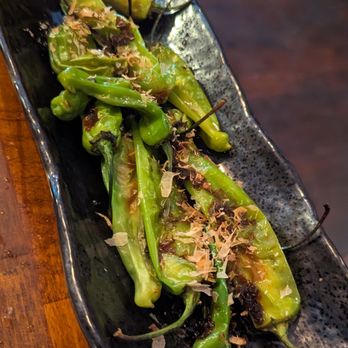 Wasan Brooklyn - Spicy grilled shishito peppers, this was delicious. Very welled seasoned. - Grilled shishito peppers with bonito flakes served on a black ceramic plate, likely at a Japanese restaurant. - Japanese Near Me - Brooklyn, New York
