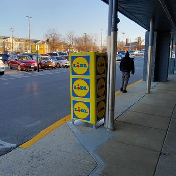 Lidl - a man walking down a sidewalk next to a parking meter - Grocery Near Me - Hyattsville, Maryland