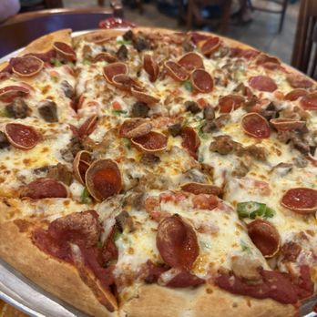 Champps Americana - Pizza - A large pizza with cheese, pepperoni, sausage, and green peppers, served on a metal tray in a restaurant setting. - American Near Me - Brookfield, Wisconsin