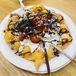 a plate of waffles topped with fruit and whipped cream