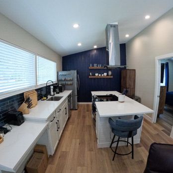 Arro Construction - Large incredible kitchen with beautiful quartz countertops, hanging vent, a spacious island for prep work & dining chairs at both ends. - General Contractors Near Me