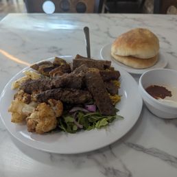 L-R fried cauliflower, kafta, gyro meat and meatballs on a bed of arugula and yellow rice