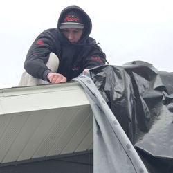 Kirkness Roofing - Jerome tarping my roof damage in the wind. This got us covered, until it was warm enough for the new roof install.