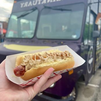 Franktuary Truck - a person holding a hot dog - Food Trucks Near Me Franktuary Truck - a person holding a hot dog - Food Trucks Near Me