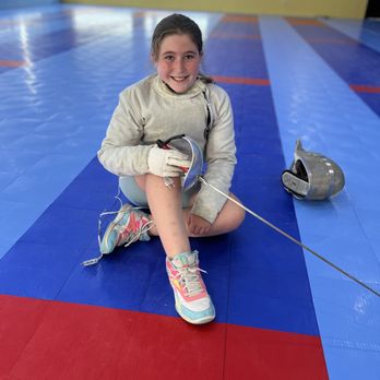 Fence St. Louis Fencing Club - A youth fencer sits on the floor Fence St. Louis fencing club with her saber and mask. - Fencing Clubs Near Me - St. Louis, Missouri Fence St. Louis Fencing Club - A youth fencer sits on the floor Fence St. Louis fencing club with her saber and mask. - Fencing Clubs Near Me - St. Louis, Missouri