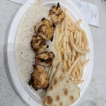 Luna Grill Mesa - A disposable plate holds grilled chicken skewers, white rice, French fries, naan bread, and receipts on a speckled table. - Mediterranean Near Me - Mesa, Arizona