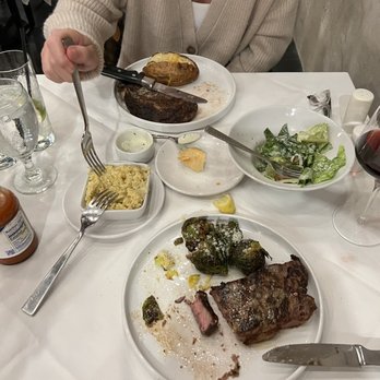 Red Board Tavern and Table - Ribeye w baked potato and iceberg lettuce salad   New York Strip with brussel sprouts and grits - New American Near Me - Navasota, Texas