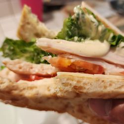 Costco Wholesale - Chicken sandwich with sauce comes with meat, lettuce, and tomato between flatbread.