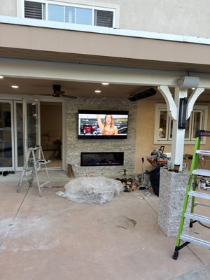 Decorative Stone — Fireplaces & Accent Walls - Decorative stone veneer installation on an outdoor fireplace wall and patio column bases. The light-colored stone adds texture and creates a coordinated look throughout the covered patio. Stone caps complete the column bases. These photos show the installation process and finished details.