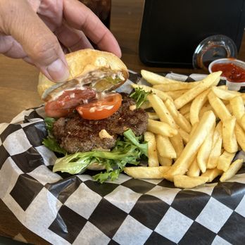 5 Ate Cafe - A burger with tomato slices, lettuce, and a beef patty, served with French fries and ketchup in the background. - Pizza Near Me - Spring, Texas
