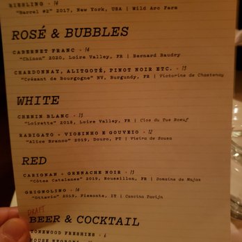 Le Caveau - a hand holding a menu - Wine Bars Near Me - Philadelphia, Pennsylvania