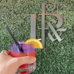 a hand holding a purple cocktail