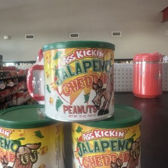 Casey's - Three cans of Ass Kickin Jalapeno Cheddar Peanuts are displayed on a store shelf, with one can stacked on top of two others. The cans feature colorful labels with a cartoon donkey and jalapeno peppers. - Pizza Near Me - Center Point, Iowa