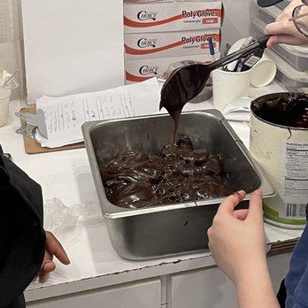 Holey Cream - a person pouring chocolate into a pan - Desserts Near Me - New York, New York Holey Cream - a person pouring chocolate into a pan - Desserts Near Me - New York, New York