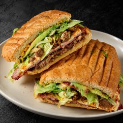 Fuego Cravings - La Fuego has milanesa de res, ham, and carne asada layered with creamy panela, tomato, lettuce, beans, onion, avocado, and FC spread.