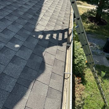 Adding Construction - after - A roof covered with asphalt shingles is shown, with a ladder leaning against the edge and a shadow cast on the shingles from the ladder. - Masonry/Concrete Near Me