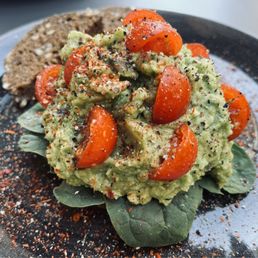 Avocado toast atop spinach with cherry tomatoes Avocado toast atop spinach with cherry tomatoes