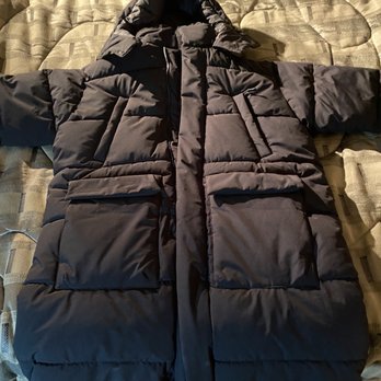Zara - My coat reduced $100 from $169.99 to $69.99.  Such a deal I have for you - A black, quilted puffer jacket with a hood is laid flat on a bed. The jacket features multiple pockets and a zipper closure, with the hood positioned at the top. The bed has a patterned comforter with a textured design, and the jacket covers most of the surface area. - Women's Clothing Near Me - Schaumburg, Illinois