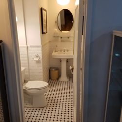 Patient bathroom at office of Natan Schleider MD fully restored with subwat tile and marble fringe walls, mosaic floor, 1920s pedestal sink