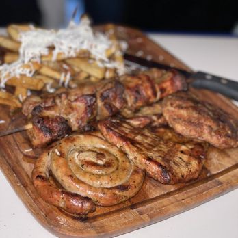 Balkanika Restaurant - a wooden cutting board with meat and potatoes - Modern European Near Me - Des Plaines, Illinois