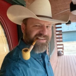 a man wearing a cowboy hat and smoking a pipe