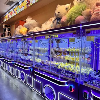 Square One Mall - Arcade claw machines filled with plush toys, including large teddy bears, are displayed in a shopping mall setting with colorful signage. - Shopping Centers Near Me - Saugus, Massachusetts