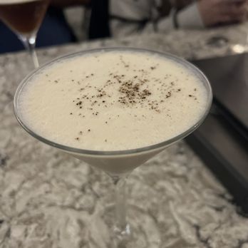 The Stuffed Olive - Caramel macchiato - A caramel macchiato served in a martini glass with a dusting of cocoa powder on top, placed on a marble bar counter. - Tapas Bars Near Me - Madison, Wisconsin