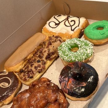 Slodoco Donuts - Espresso cream, apple fritter, maple bar, maple bar with bacon, pb&j pillow (white icing), mint, matcha w/coconut, and marshmallow galaxy - Donuts Near Me - Goleta, California Slodoco Donuts - Espresso cream, apple fritter, maple bar, maple bar with bacon, pb&j pillow (white icing), mint, matcha w/coconut, and marshmallow galaxy - Donuts Near Me - Goleta, California